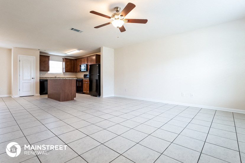 an empty living room and kitchen with a ceiling fan
