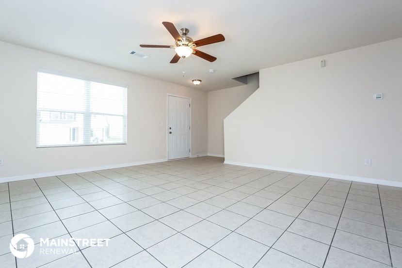 a clean and empty living room with a ceiling fan