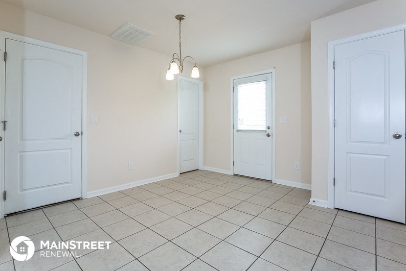 an empty living room with two white doors and a tiled floor