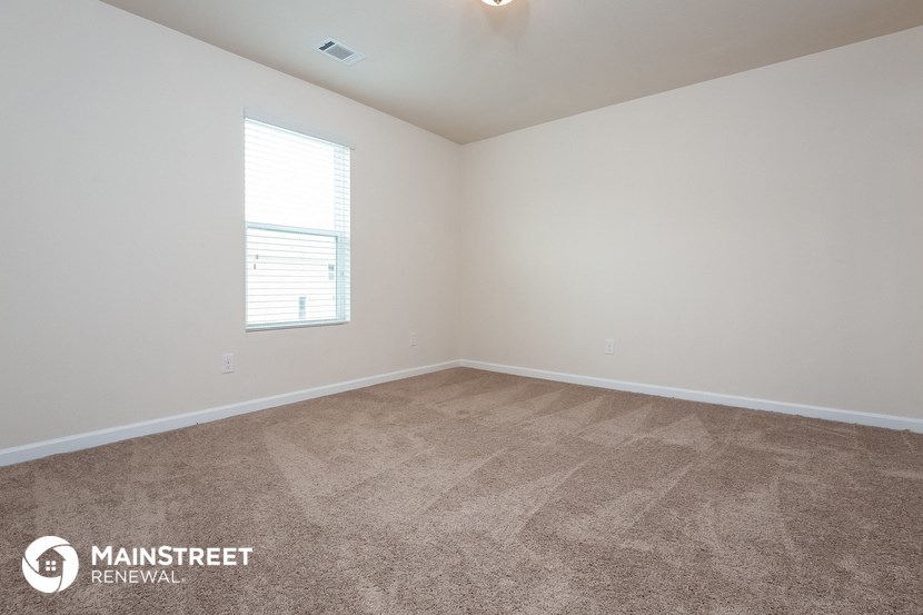 the spacious living room with carpeting and a window