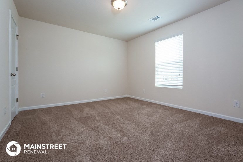the spacious living room with carpeting and a window