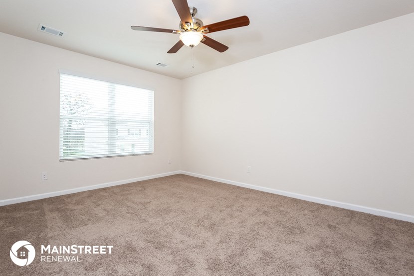 the spacious living room with carpeting and a ceiling fan