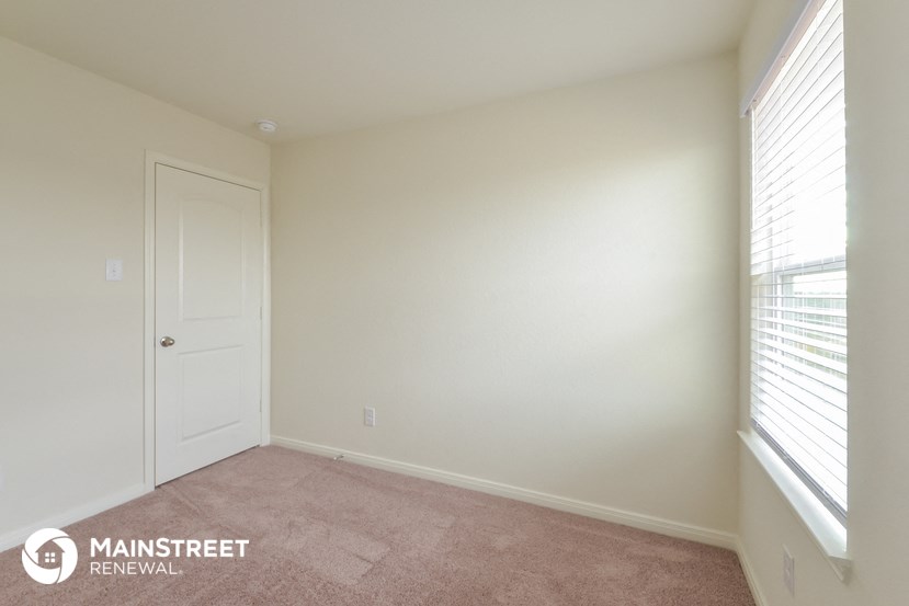 a bedroom with white walls and a door and a window