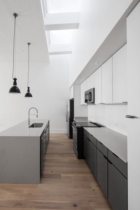 a kitchen with white cabinets and black appliances and a wood floor