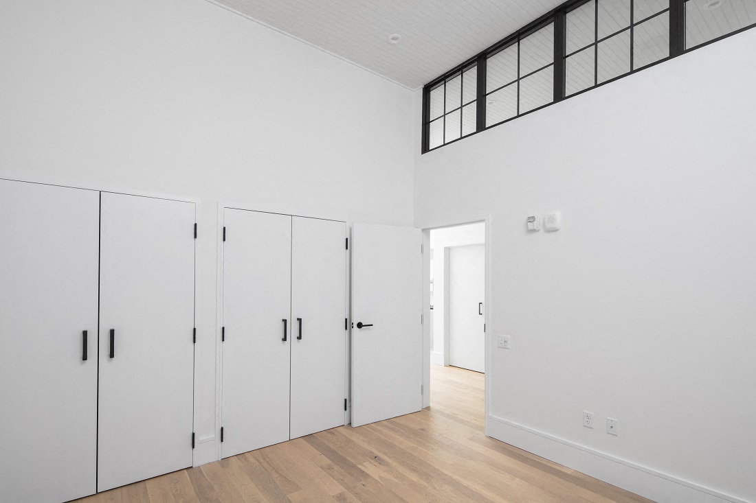 a white room with white closets and a window