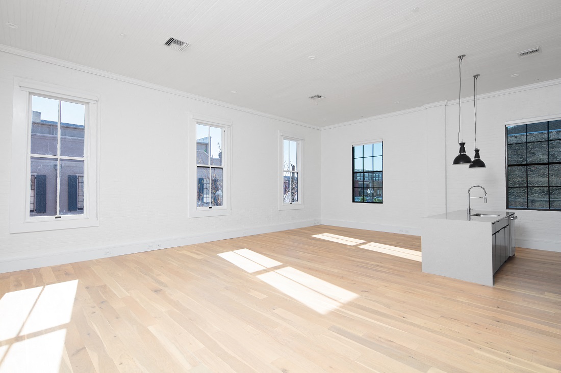 an open kitchen and living room with white walls and wood floors