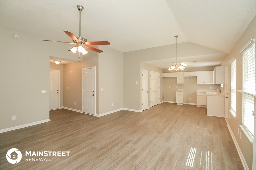 a spacious living room with a ceiling fan and a kitchen