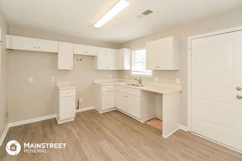 a kitchen with white cabinets and a sink and a window