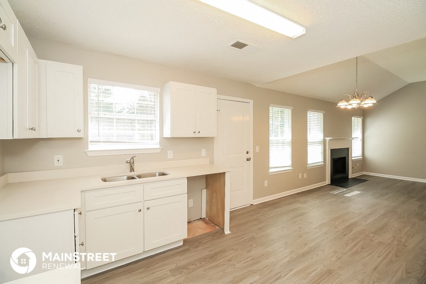 a kitchen and living room with white cabinets and a wood floor