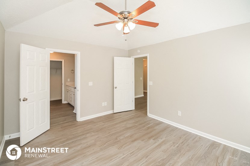the spacious living room of this manufactured home has a ceiling fan and wood flooring