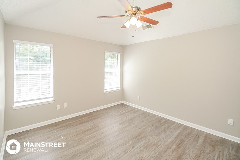 the spacious living room with wood floors and a ceiling fan