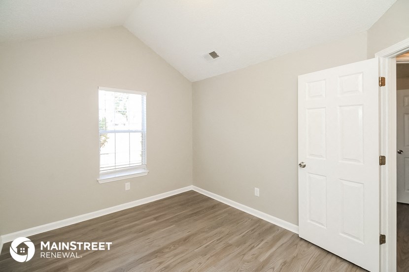a bedroom with a white door and wood flooring