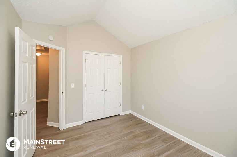 the living room of an apartment with wood floors and a white door