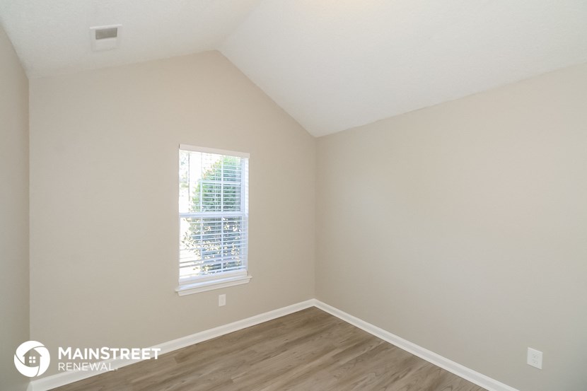the upstairs bedroom with hardwood flooring and a window
