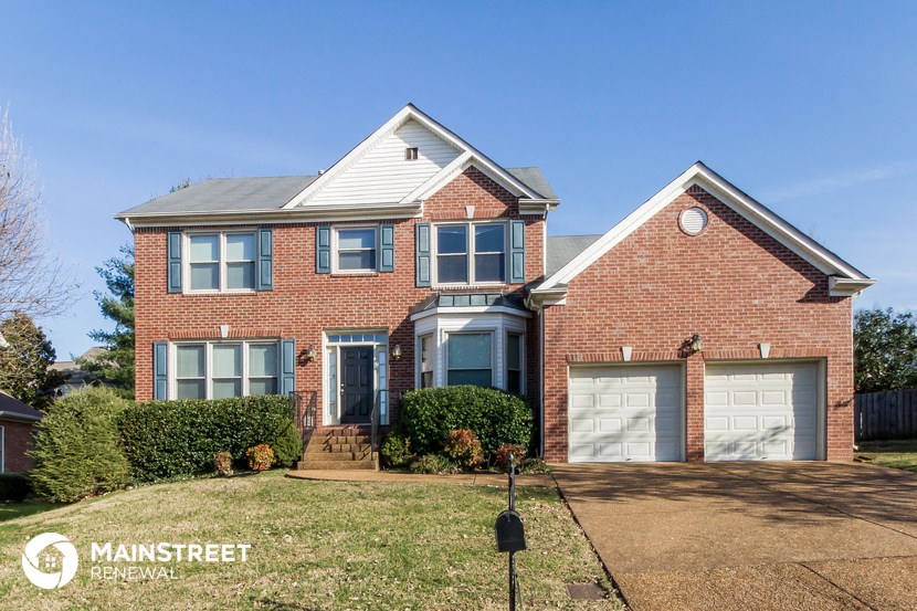a brick house with two garage doors and a lawn