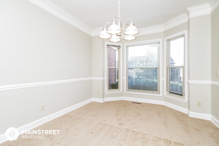 an empty dining room with three windows and a chandelier