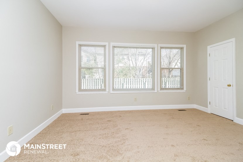 a empty living room with three windows and a white door