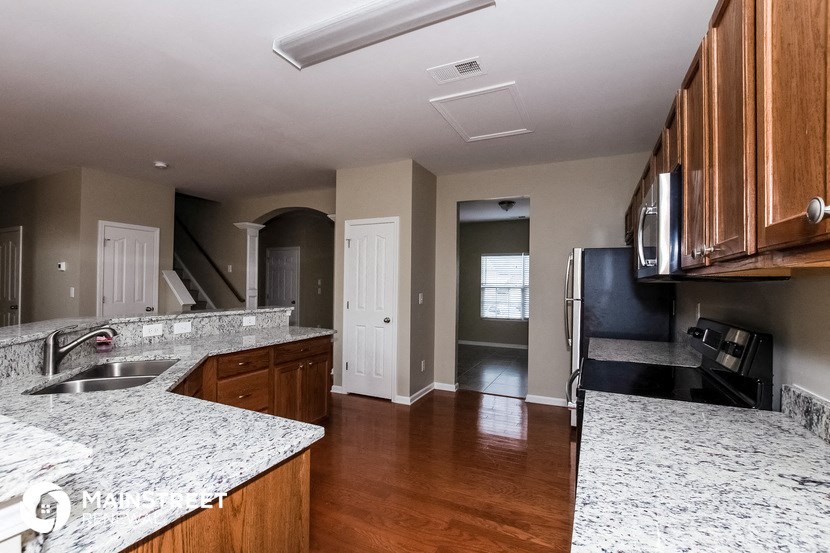 an empty kitchen with marble counter tops and wooden cabinets
