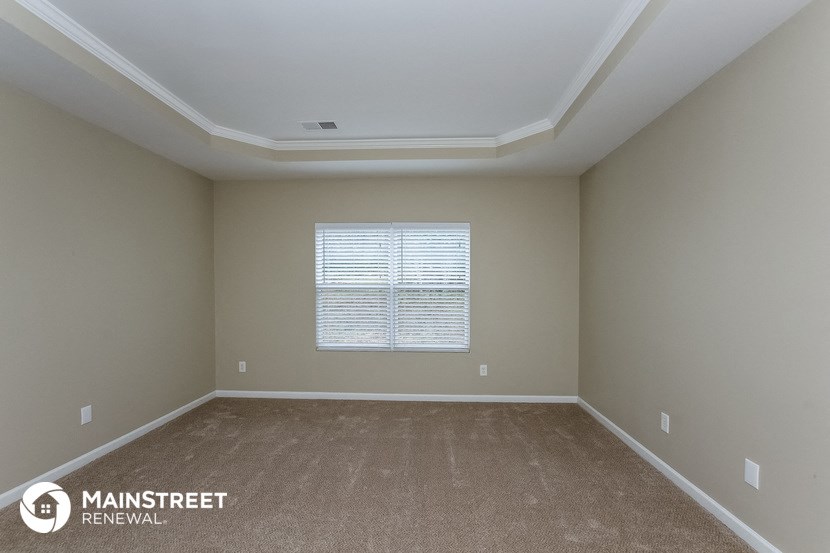 a large empty room with carpet and a window