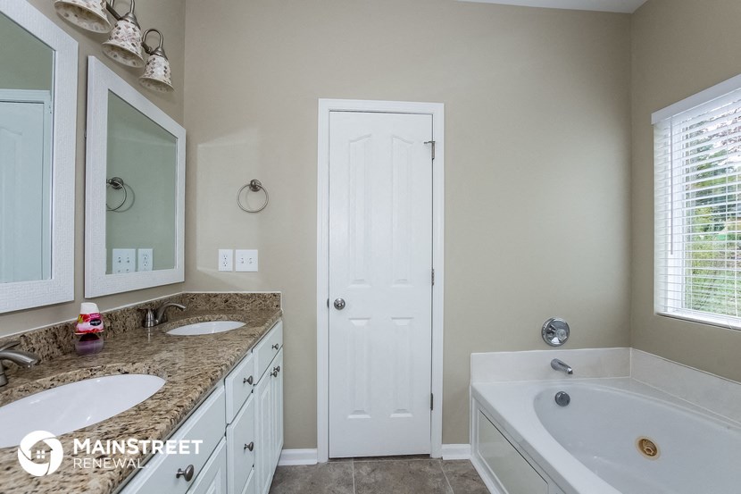 a bathroom with two sinks and a tub and a white door