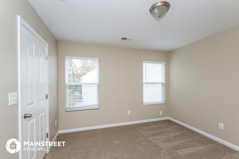 the master bedroom has carpeted floors and a white door