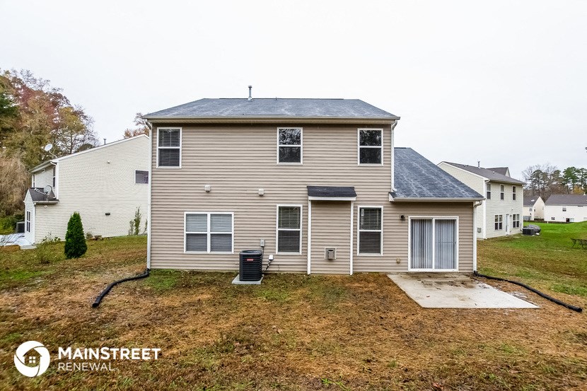 the back of a house with a yard and a trash can