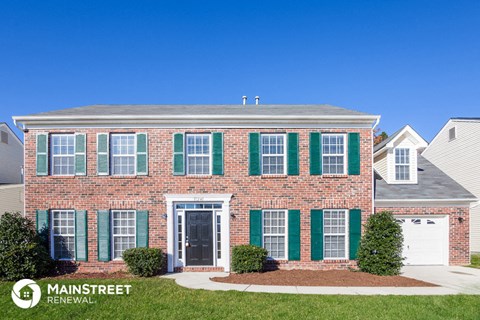 a brick house with green shutters and a blue sky