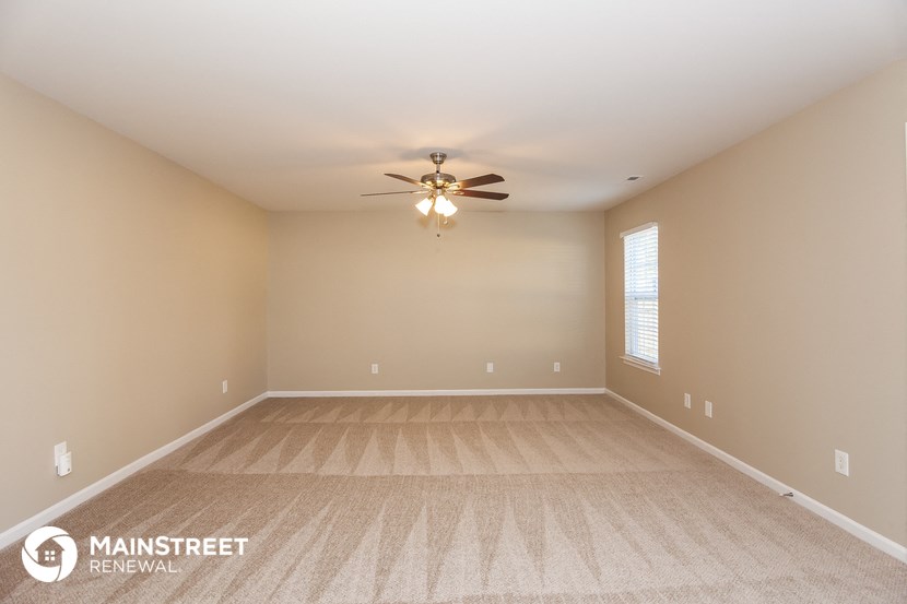 the spacious living room with carpet and ceiling fan