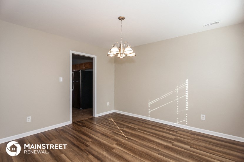 a spacious living room with wood flooring and a door to the hallway