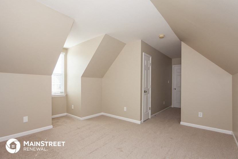 the upstairs bedroom with vaulted ceilings and a door to the closet