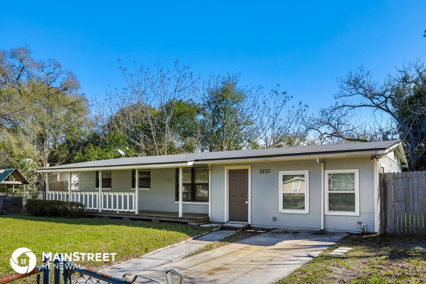 a small white house with a porch and a lawn