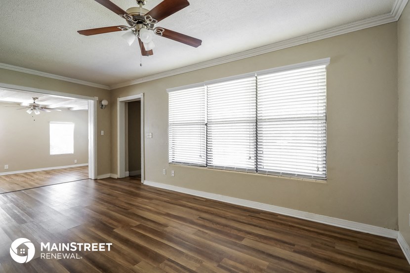 the spacious living room with a ceiling fan and a large window