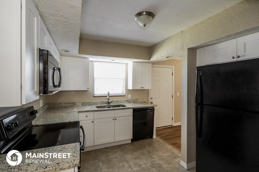 a kitchen with white cabinets and black appliances