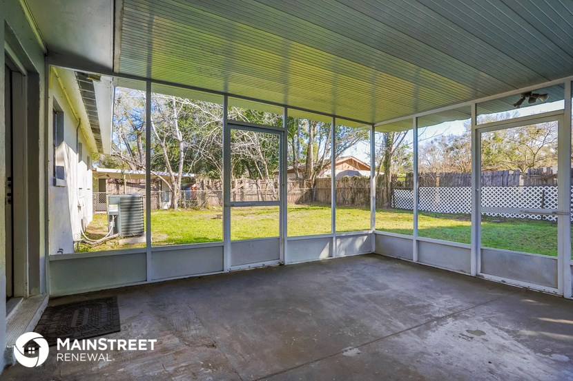 a screened in porch with glass doors and a backyard