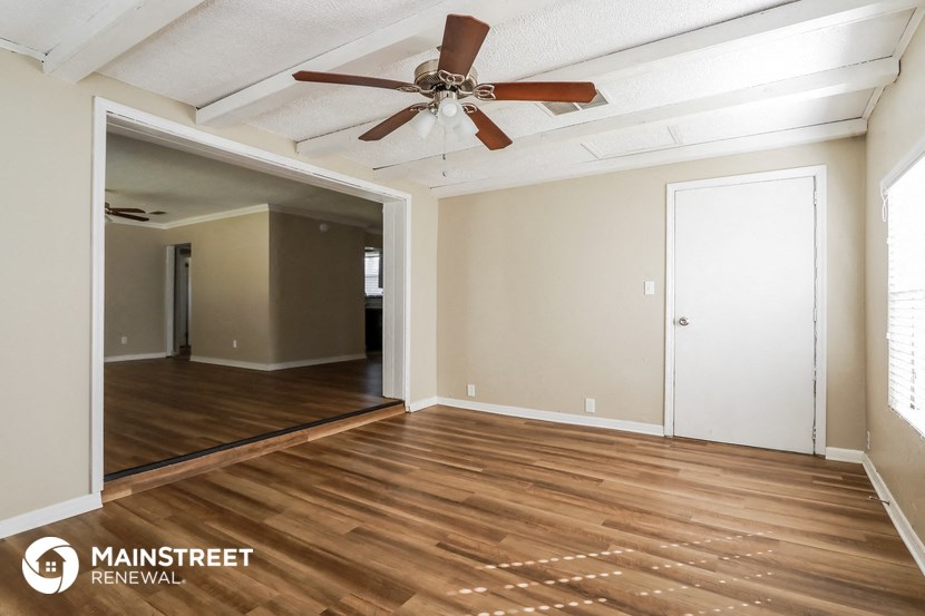 the living room and dining room with wood floors and a ceiling fan