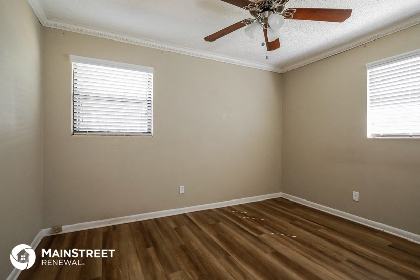 the spacious living room with wood floors and a ceiling fan