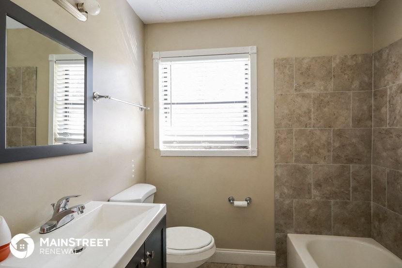 a bathroom with a sink toilet and a mirror and a window