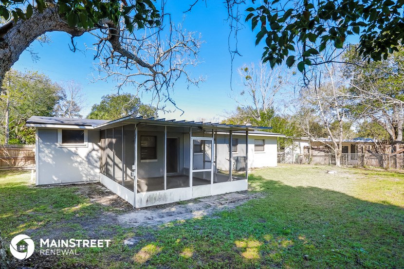 a small white house with a yard and a tree