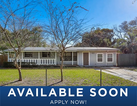 a small white house with a yard and trees