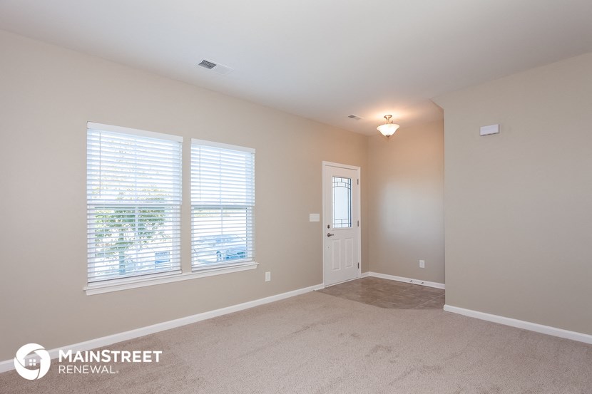 the living room of a house with a large window and a door