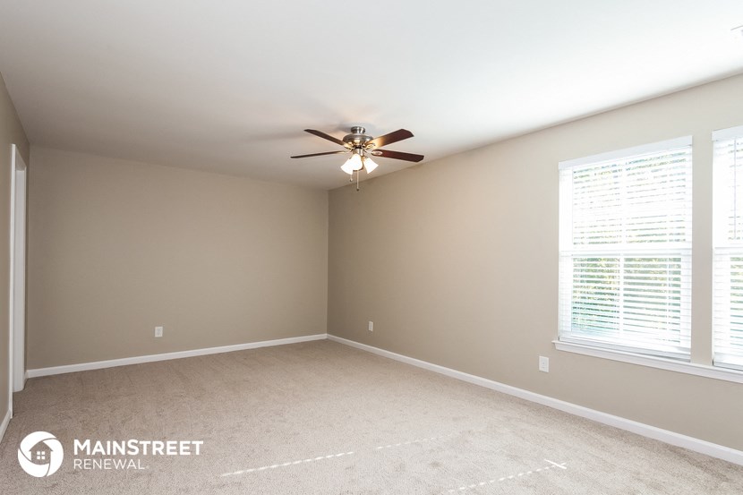 a bedroom with a ceiling fan and a large window