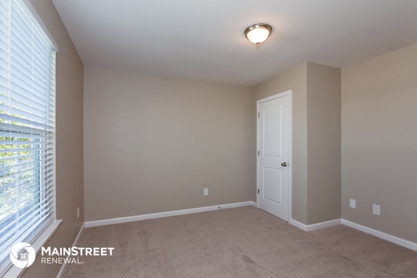 the master bedroom has a large window and carpeted flooring