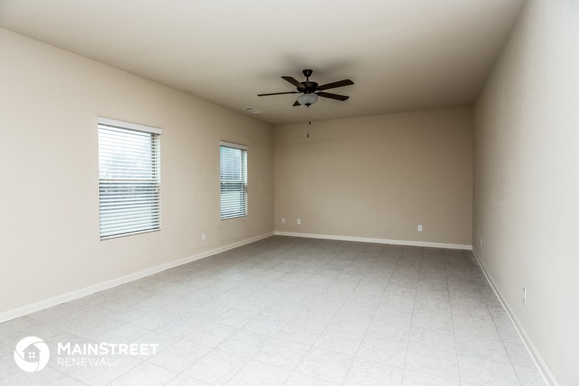 an empty living room with a ceiling fan