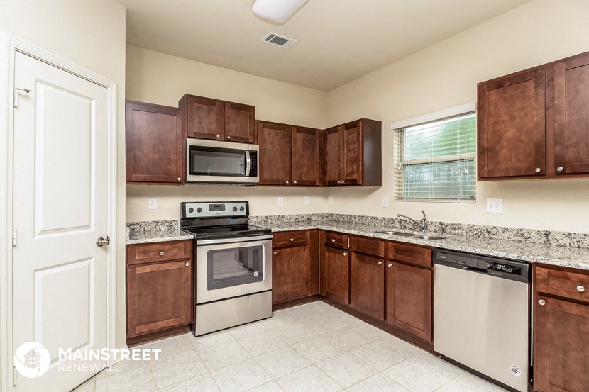 a kitchen with wooden cabinets and white appliances and granite counter tops