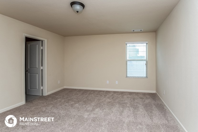 the spacious living room with carpeted flooring and a window