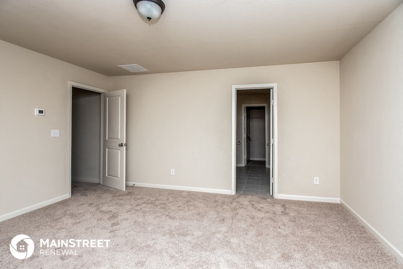 a master bedroom with two doors and a carpeted floor
