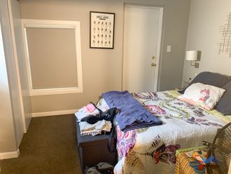 a bedroom with a bed and a dresser with clothes on it