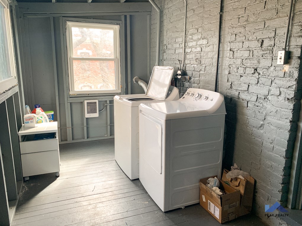 a white washing machine in a room with a sink and a window