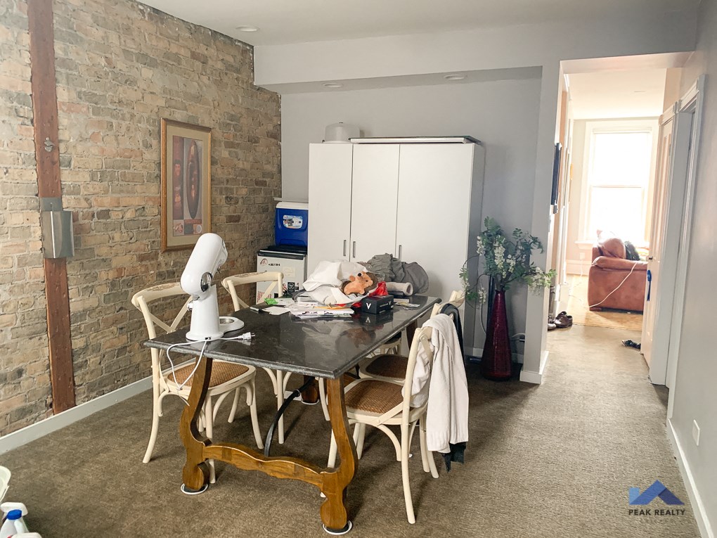 a dining room with a table and chairs and a brick wall