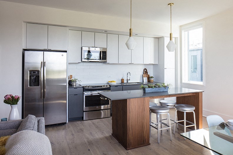 a kitchen with white cabinets and stainless steel appliances and a bar with stools